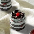 Gluten free Black Forest jar cake with chocolate layers, whipped cream, and cherries in a glass jar